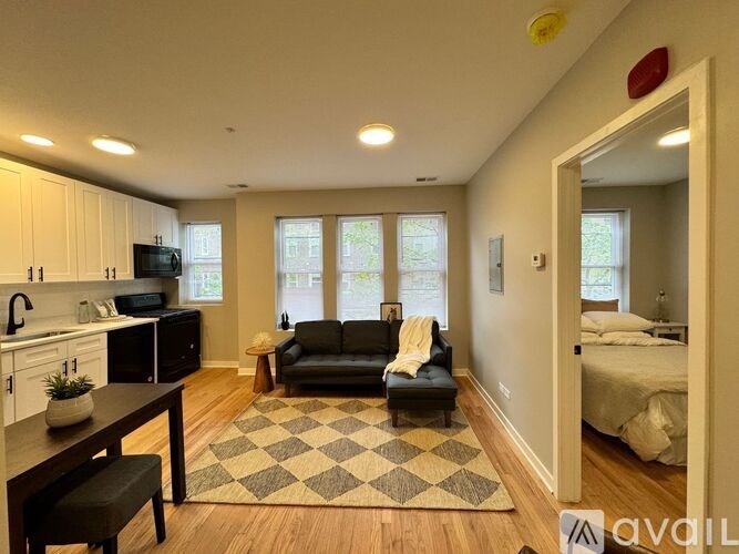 A living room with a black couch and a checkered rug.