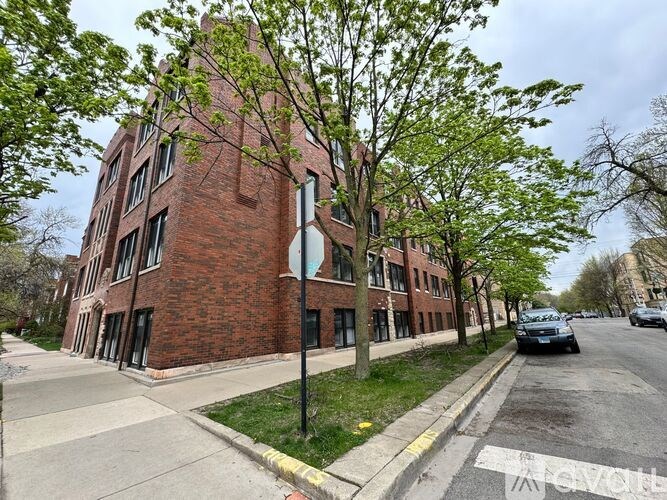 A street view of a red brick building with a tree in front.