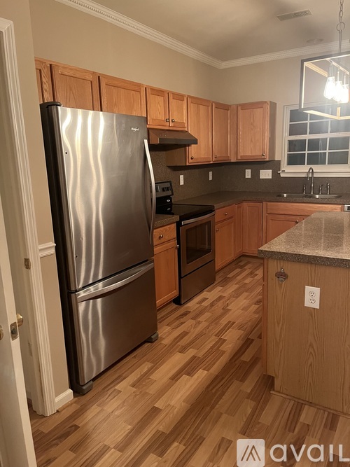A kitchen with a stainless steel refrigerator and wooden cabinets.