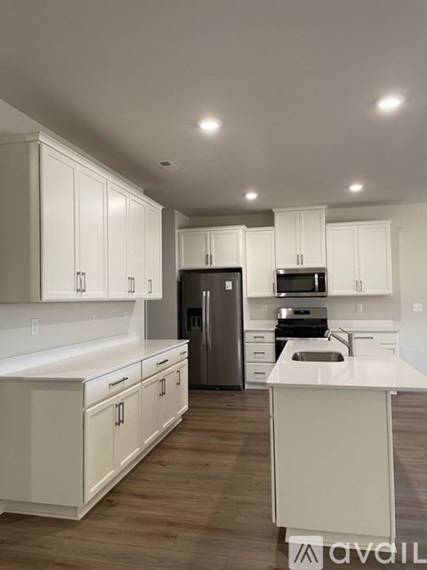 A modern kitchen with white cabinets and wooden floors.