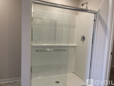 A glass shower stall with a silver handle.