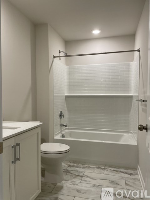 A white bathroom with a toilet, sink, and bathtub.