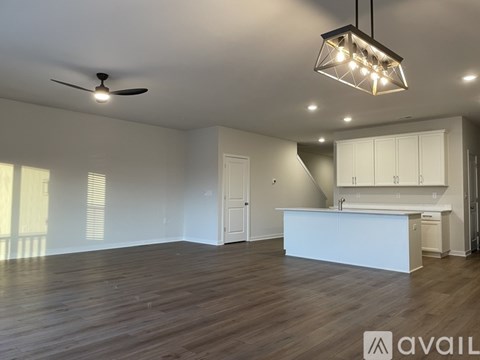 A spacious room with a kitchen area and a ceiling fan.