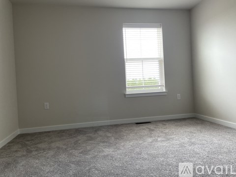 A room with a carpeted floor and a window with blinds.