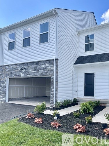 A white house with a black door and a stone wall.