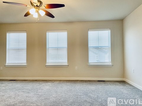 A room with a ceiling fan and three windows.