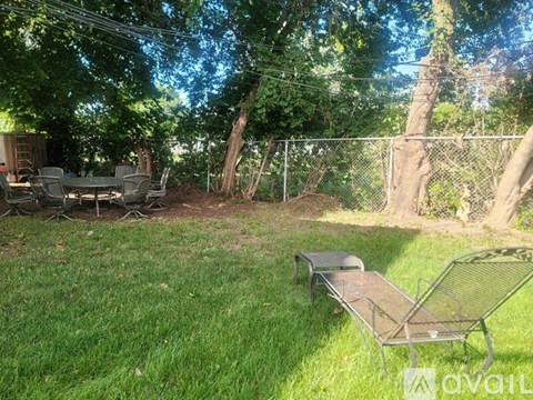 A backyard with a lawn, chairs, and trees.