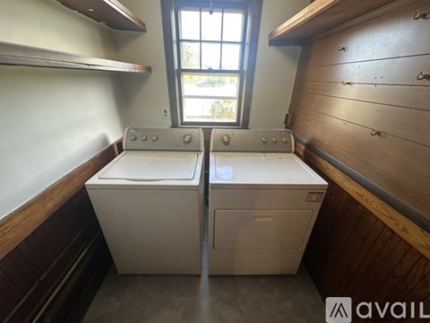 A laundry room with two washers and a window.