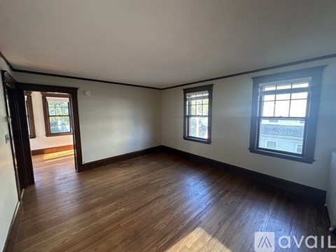 A room with wooden floors and two windows.