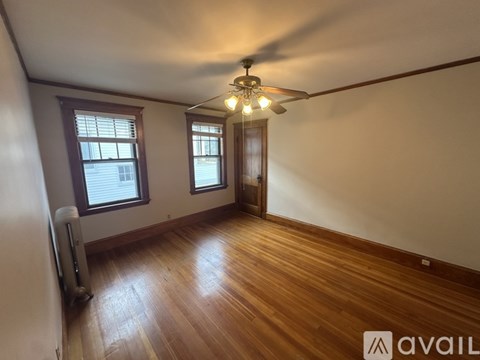 A room with wooden floors and a ceiling fan with lights.