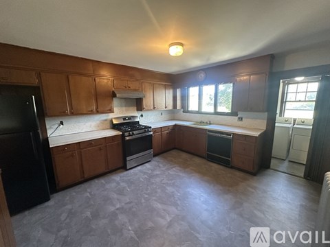 A kitchen with brown cabinets and a black fridge.