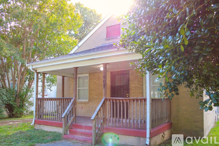 A house with a porch and a tree in front of it.