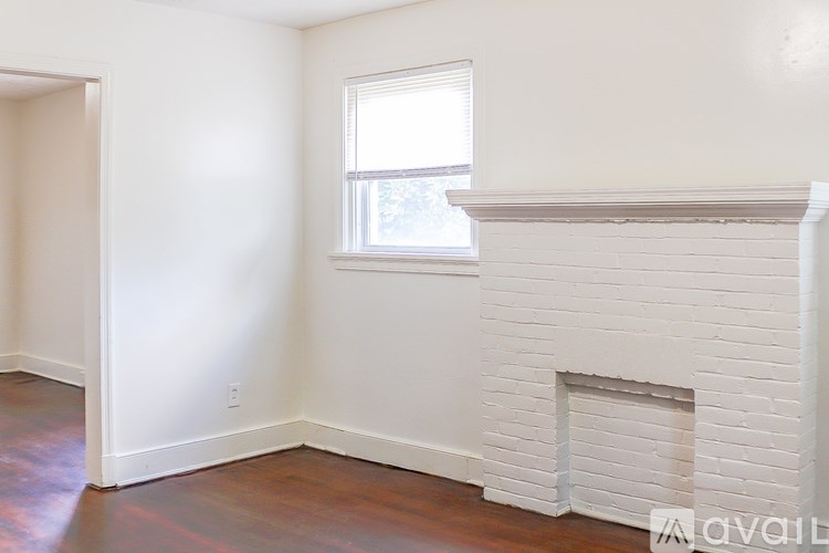 A white fireplace in a room with a window.