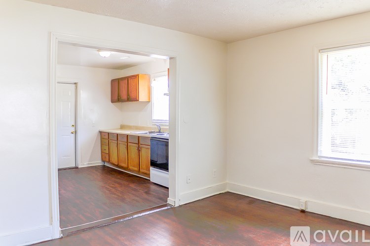 A room with a wooden floor and a window with blinds.