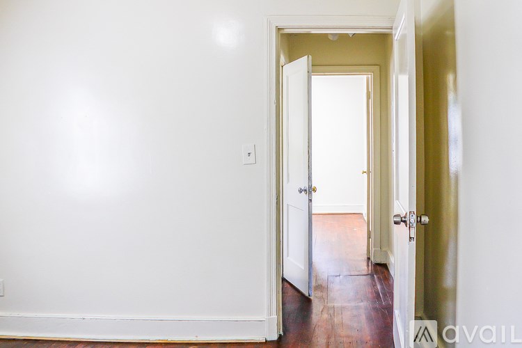 A hallway with a door on the right and a wall on the left.