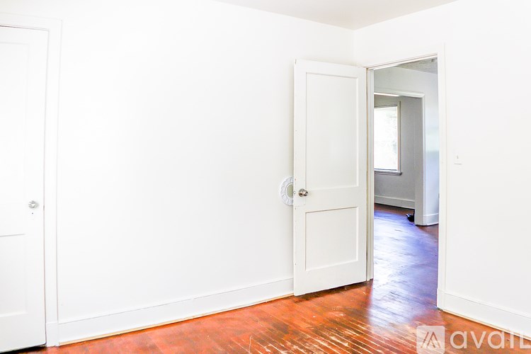 A room with a white door and a wooden floor.