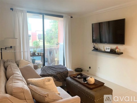 A living room with a brown couch and a flat screen TV mounted on the wall.
