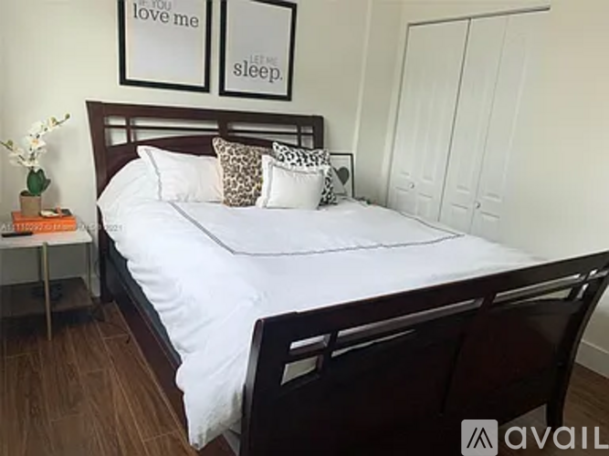 A bedroom with a bed, a nightstand, and two framed pictures on the wall.