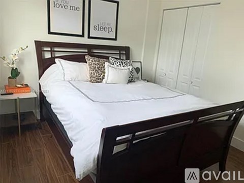 A bedroom with a bed, a nightstand, and two framed pictures on the wall.