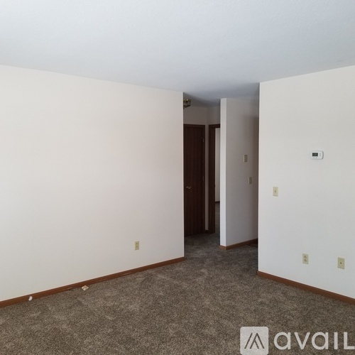 A room with a carpeted floor and a doorway leading to another room.