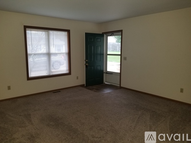 Empty room with a carpeted floor and a door leading to a balcony.