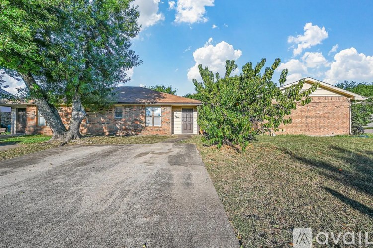 A house with a driveway and trees in front of it.