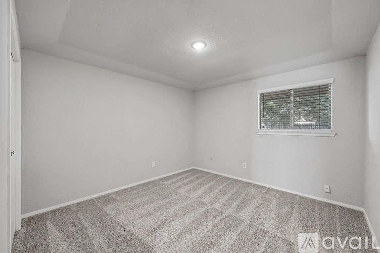 A room with a carpeted floor and a window with blinds.