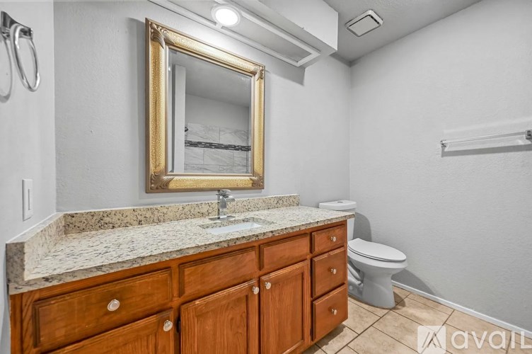 A bathroom with a granite countertop and a mirror above it.