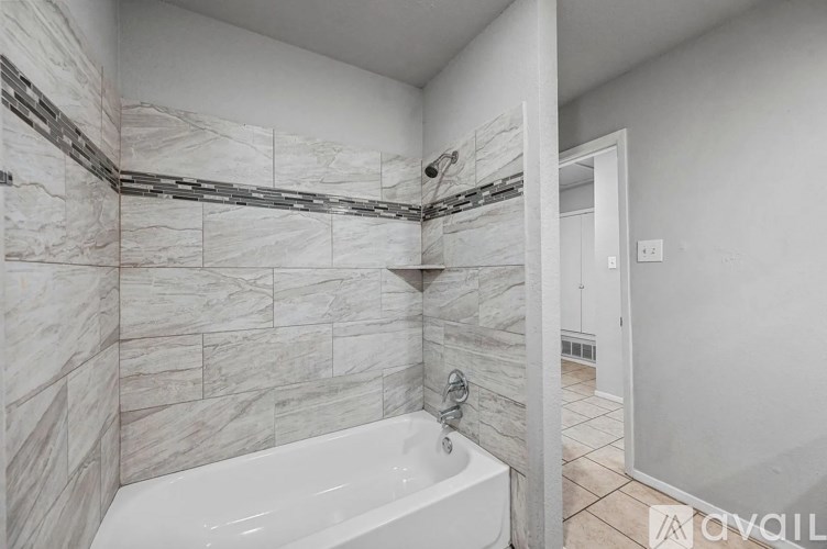 A bathroom with a marble tile wall and a white bathtub.