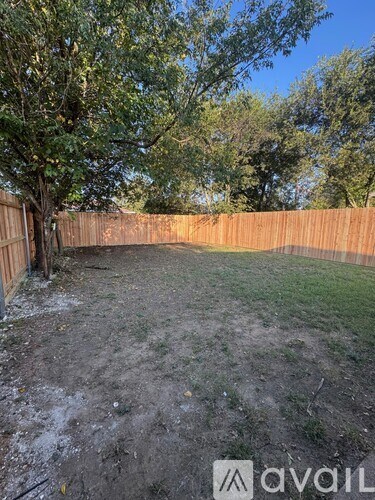A backyard with a fence and a tree.