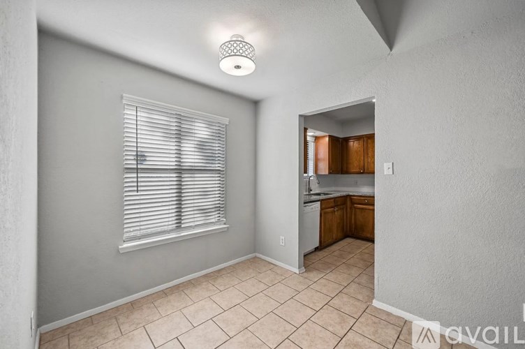 A room with a window and a kitchen area in the background.