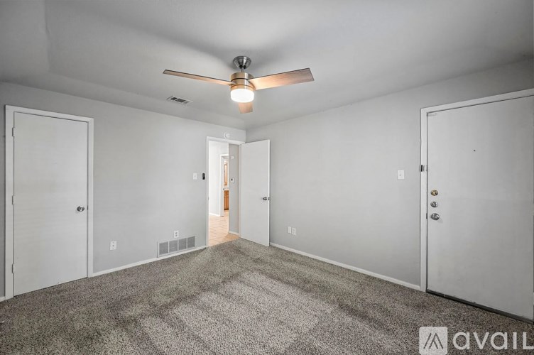 A room with a carpeted floor and a ceiling fan.