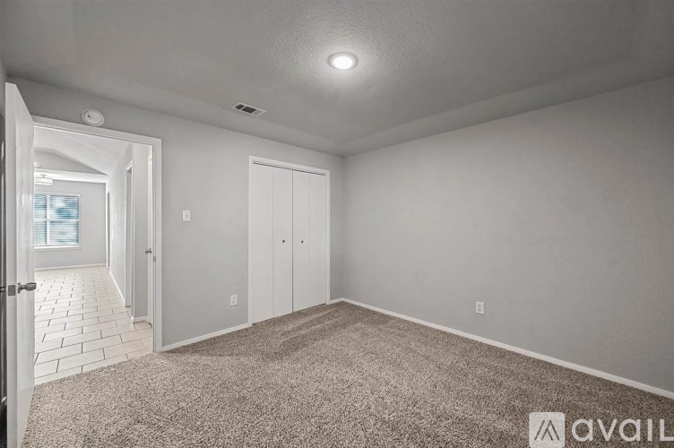 A room with a carpeted floor and a door leading to another room.