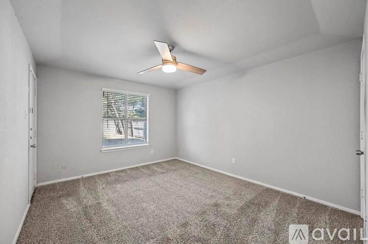 A room with a ceiling fan and a window with blinds.