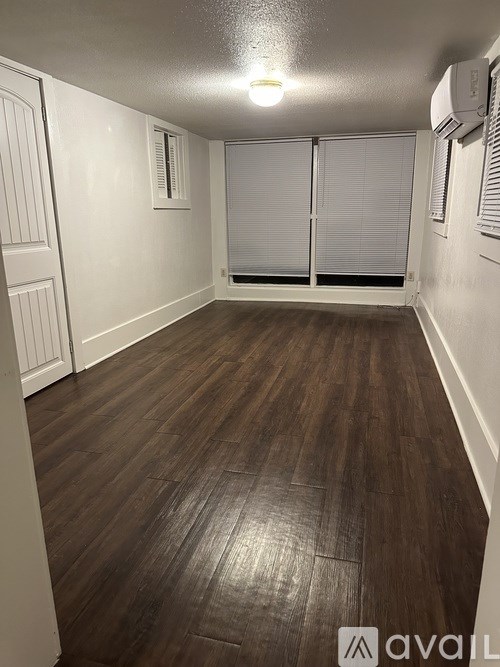 A room with wooden flooring and white walls.