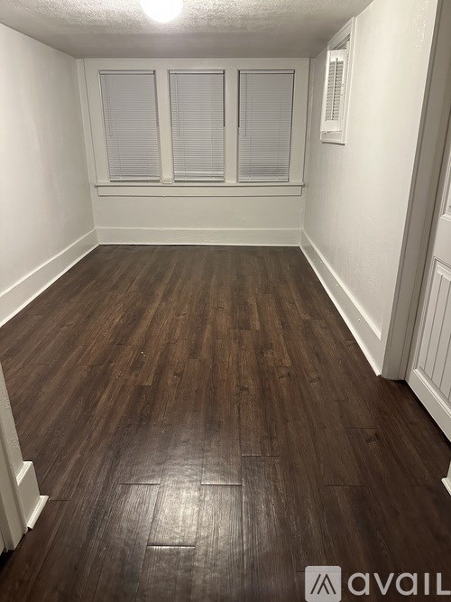 A room with wooden flooring and white walls.