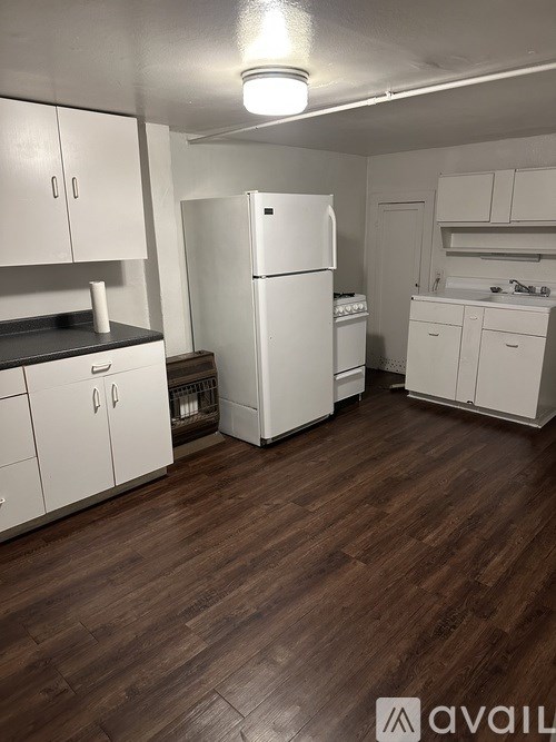 A kitchen with white appliances and wooden floors.