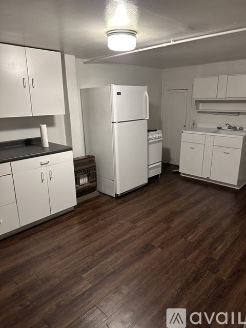 A kitchen with white appliances and wooden floors.