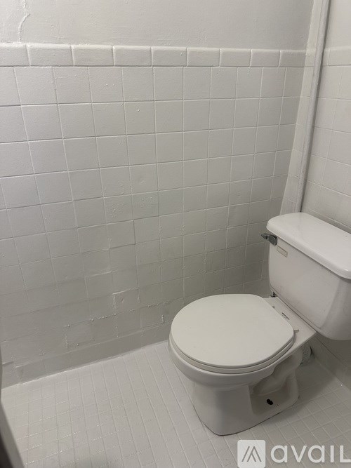 A white toilet in a bathroom with white tiled walls.