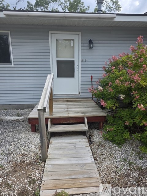 A white door is on a grey house with a wooden step.