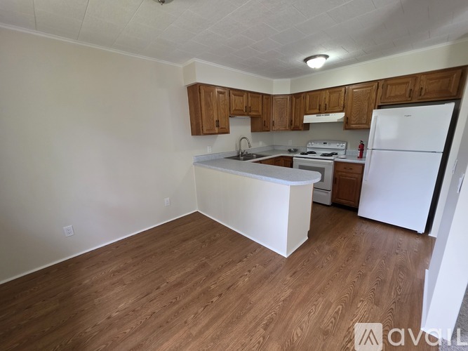 A kitchen with white appliances and wooden cabinets.