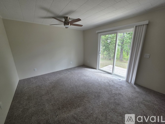 A room with a ceiling fan and carpeted floor.