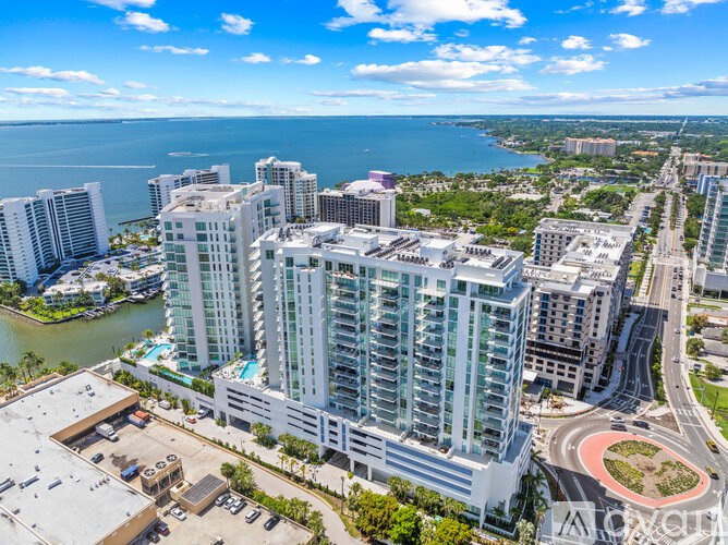 A view of a city with a large building in the foreground and a body of water in the background.