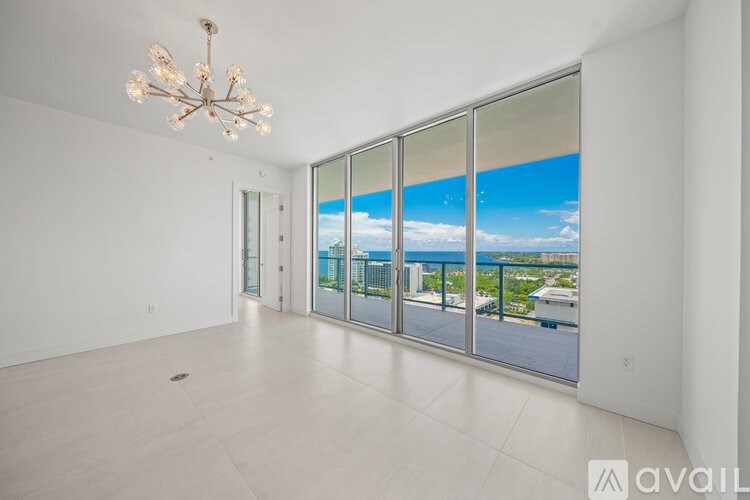 A large empty room with a chandelier and a view of the outside through the windows.