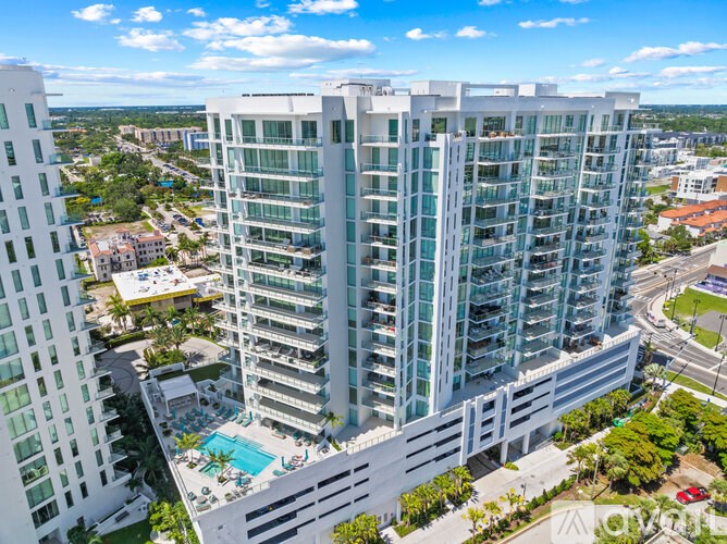 A tall white building with a pool in front.