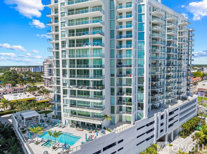 A tall white building with a pool in front.
