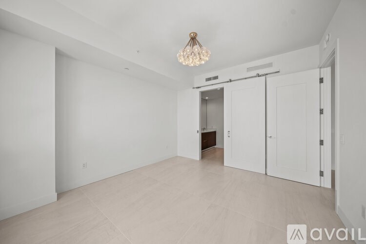 A spacious room with a chandelier and a sliding door.