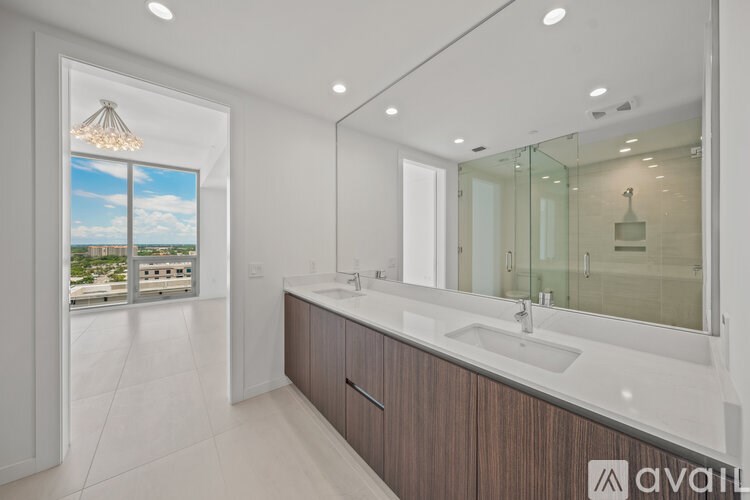 A modern bathroom with a large mirror and a view of the city.