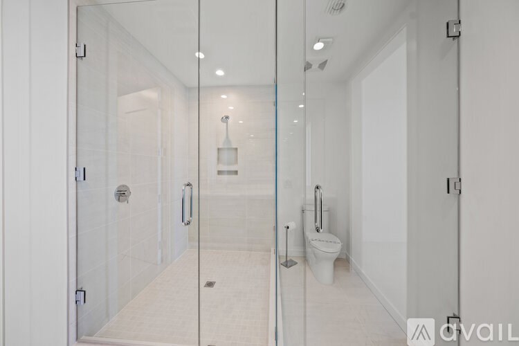 A white bathroom with a glass shower door and a toilet.