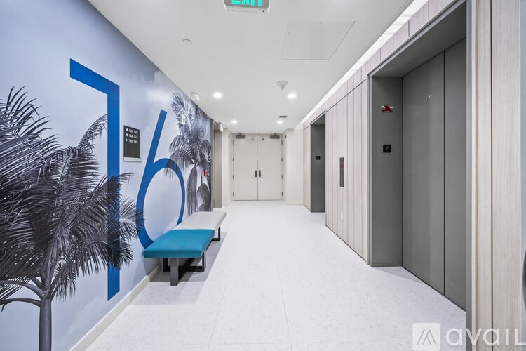 A long hallway with a bench and a wall with a palm tree and the number 76 on it.